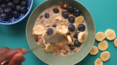Düz manzaralı kişi mutfakta meyveli müsli gevreği hazırlıyor.
