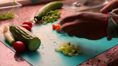 Erkek elleri ahşap kesim tahtasında sebze hazırlıyor.