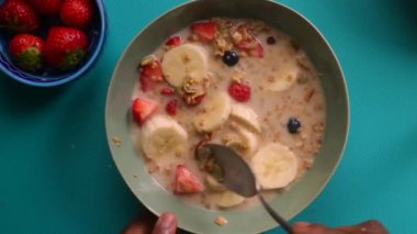 Müsli gevreğini meyvelerle hazırlayan kişinin düz bir görüntüsü vardı.
