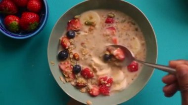 Düz açılı insan sağlıklı müsli gevreğini meyvelerle hazırlıyor.