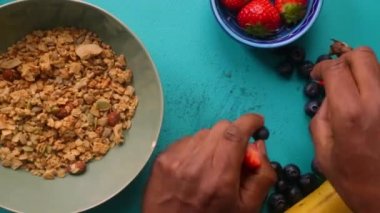 Sağlıklı müsli gevreğini meyvelerle hazırlayan kişinin düz bir görüntüsü vardı.