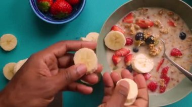 Düz manzaralı biri sağlıklı müsli gevreğini meyvelerle hazırlıyor.