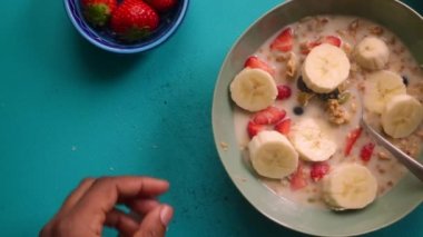 Düz manzaralı biri sağlıklı müsli gevreğini meyvelerle hazırlıyor.