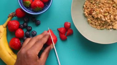 Düz manzaralı biri sağlıklı müsli gevreğini meyvelerle hazırlıyor.
