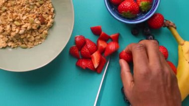 Düz manzaralı biri sağlıklı müsli gevreğini meyvelerle hazırlıyor.