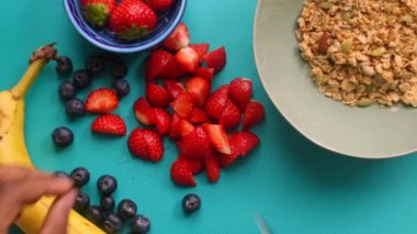 Düz manzaralı biri sağlıklı müsli gevreğini meyvelerle hazırlıyor.