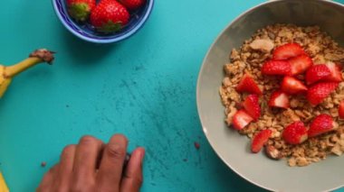 Düz manzaralı biri sağlıklı müsli gevreğini meyvelerle hazırlıyor.