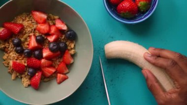 Düz manzaralı biri sağlıklı müsli gevreğini meyvelerle hazırlıyor.