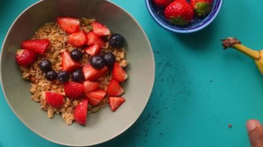 Düz manzaralı biri sağlıklı müsli gevreğini meyvelerle hazırlıyor.