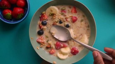 Müsli gevreğini meyvelerle hazırlayan kişinin düz bir görüntüsü vardı.