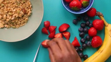 Düz manzaralı kişi müsli gevreğini meyvelerle hazırlıyor.