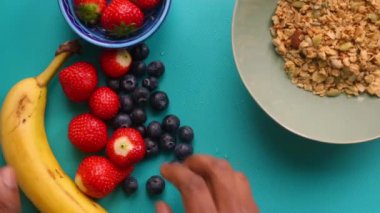 Düz manzaralı kişi müsli gevreğini meyvelerle hazırlıyor.