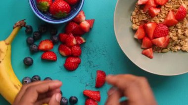 Düz manzaralı kişi müsli gevreğini meyvelerle hazırlıyor.