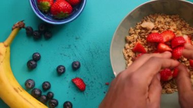Düz manzaralı kişi müsli gevreğini meyvelerle hazırlıyor.