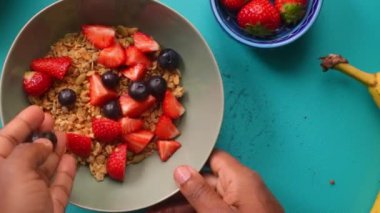Düz manzaralı kişi müsli gevreğini meyvelerle hazırlıyor.