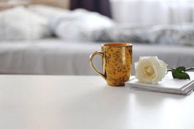 Sarı fincan ve çiçek sabah yatağının arka planında duruyor.