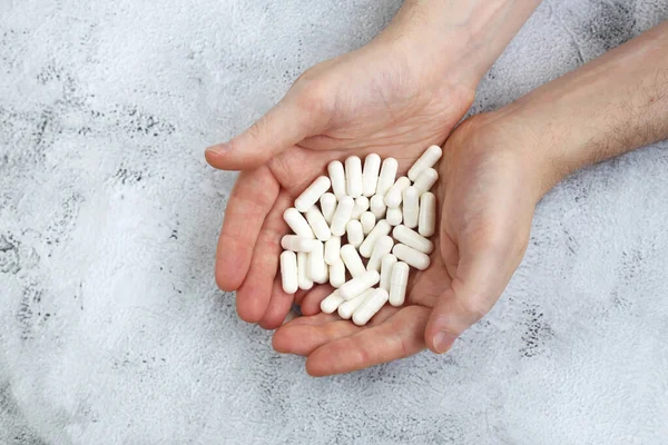 handful of white pills in the hands of man