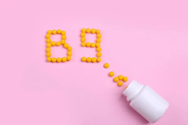 Vitaminler pembe bir zemin üzerine dağılmış, tıpkı B9 harfi gibi. 