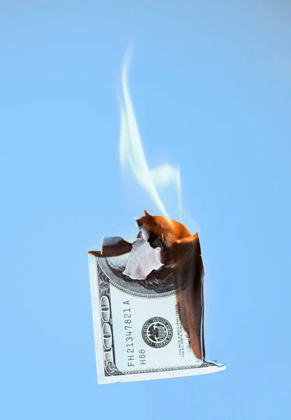 Burning hundred dollars cash on blue background — Stock Photo, Image