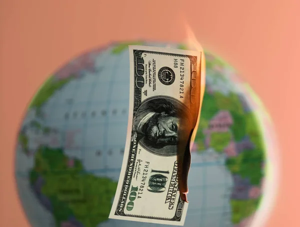 Burning hundred dollars cash and globe behind on the background. — Stock Photo, Image