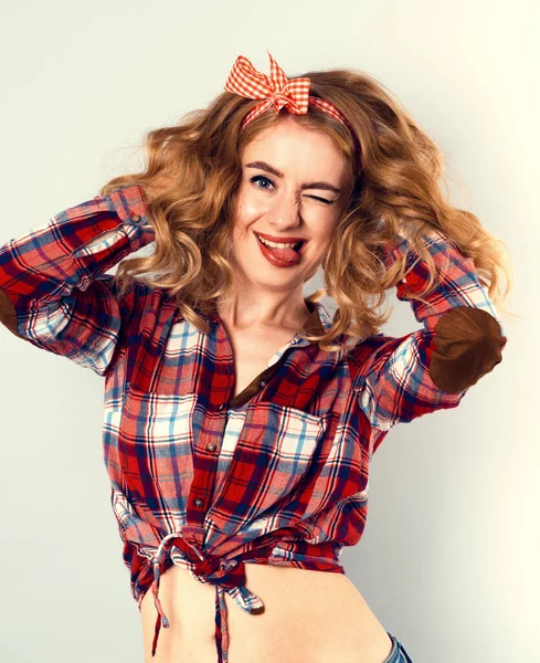 Pin-up flicka med lockigt blont hår med röd rutig rosett och skjorta bär jeans shorts. — Stockfoto