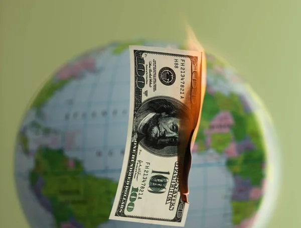 Burning hundred dollars cash and globe behind on the background. — Stock Photo, Image