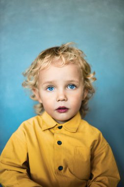 Altın saçlı ve mavi gözlü sevimli küçük çocuk.