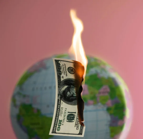 Burning hundred dollars cash and globe behind on the background. — Stock Photo, Image