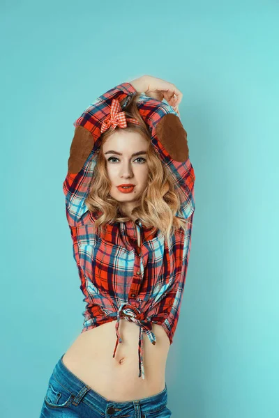 Pin-up dívka s kudrnaté blond vlasy s červenou kostkovanou mašlí a košile na sobě džíny kraťasy. — Stock fotografie