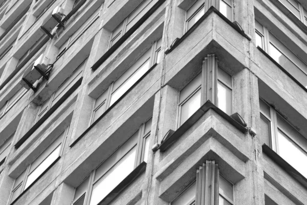 Black and white corner of a building with windows.