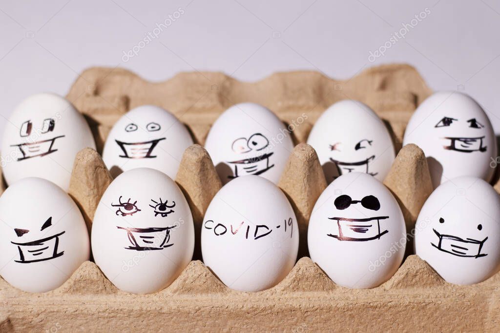 White eggs with painted faces in a box on a light background