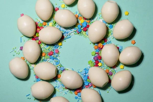 Beyaz çikolatalı yumurta çemberi ve yeşil arka planda renkli tatlı tozu. — Stok fotoğraf