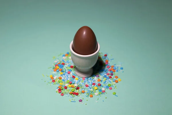 Beyaz yumurta standında yeşil arka planda tatlı tozlu bir çikolata yumurtası. — Stok fotoğraf