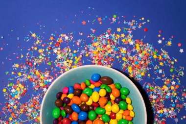 Şekerlerle dolu kase mavi arka planda yatıyordu.