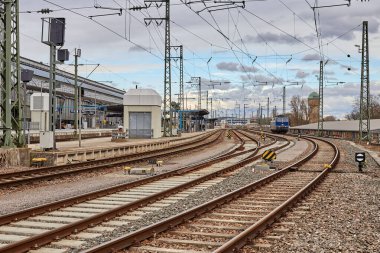 Karlsruhe 'deki tren istasyonu bulutlu bir havada. Raylarda mavi bir lokomotif.