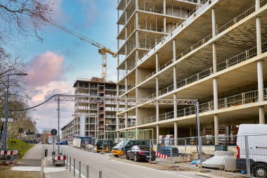 Caddedeki ticari bir bina için inşaat alanı, mavi gökyüzünün altında vinçler..