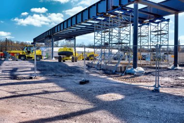 Mavi gökyüzünün altında bir köprü, inşaat makineleri ve kazıcılar inşa ediliyor.