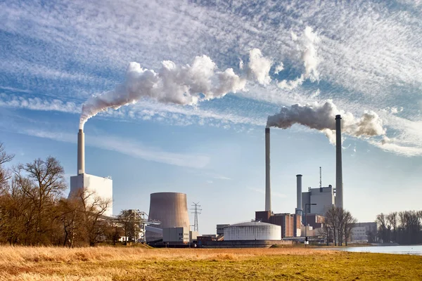 Power plant with chimneys and smoke under blue sky