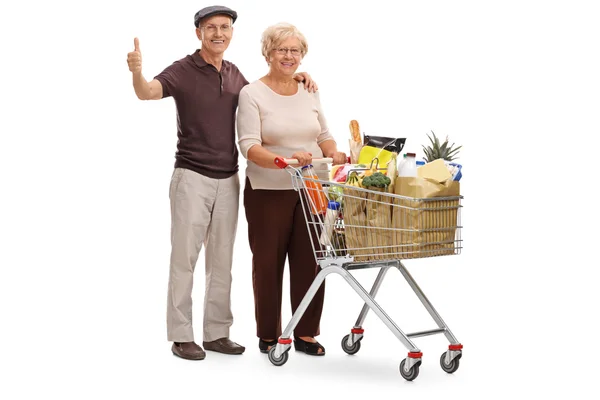 Elderly couple with shopping cart and thumb up — Stock Photo, Image