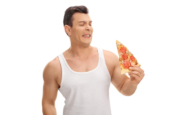 Äcklad kille tittar på en bit pizza — Stockfoto