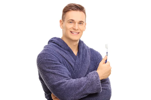 Komea kaveri kylpytakissa pitelemässä hammasharjaa. — kuvapankkivalokuva