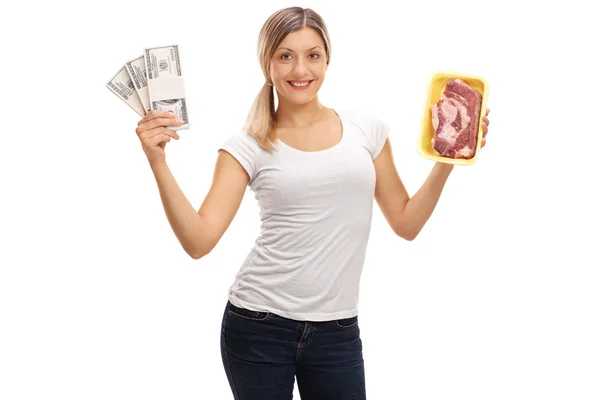 Kobieta trzyma stosy pieniędzy i stek — Zdjęcie stockowe