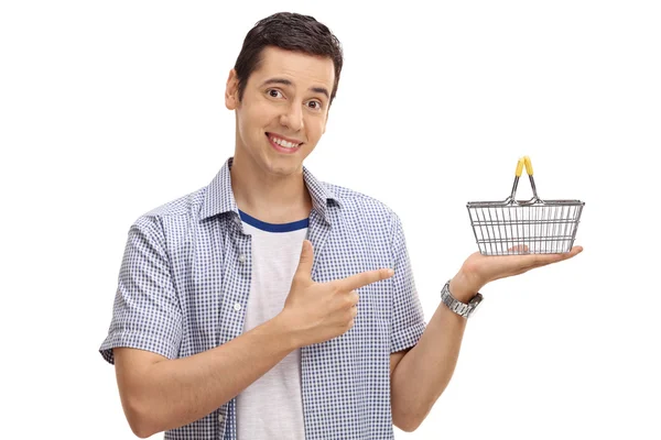 Homem segurando uma pequena cesta de compras vazia e apontando — Fotografia de Stock