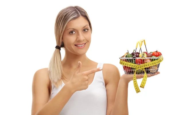 Mujer sosteniendo una pequeña cesta de la compra y señalando —  Fotos de Stock