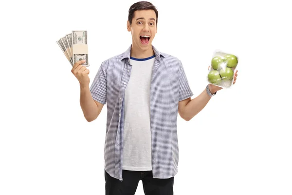 Un type qui tient des paquets d'argent et un paquet de pommes. — Photo