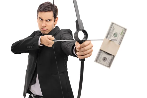 Businessman aiming with bow and arrow with money — Stock Photo, Image