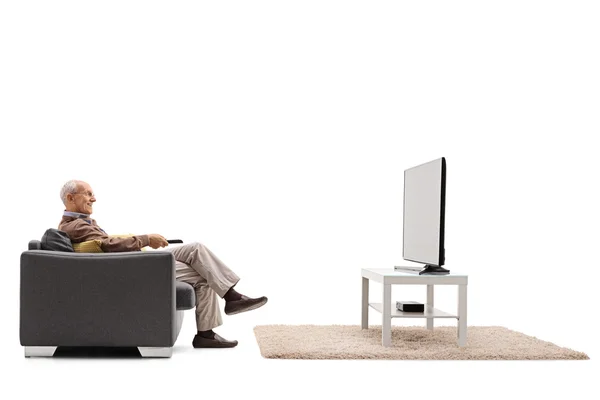 Senior yang gembira duduk di kursi dan menonton televisi — Stok Foto