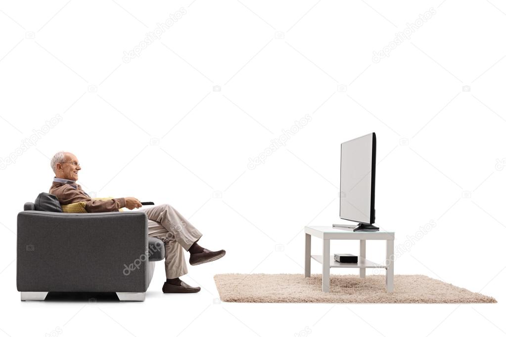 Joyful senior sitting in an armchair and watching television