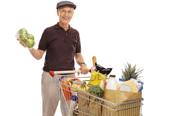 Homem posando com um pacote de maçã e carrinho de compras — Fotografia de Stock