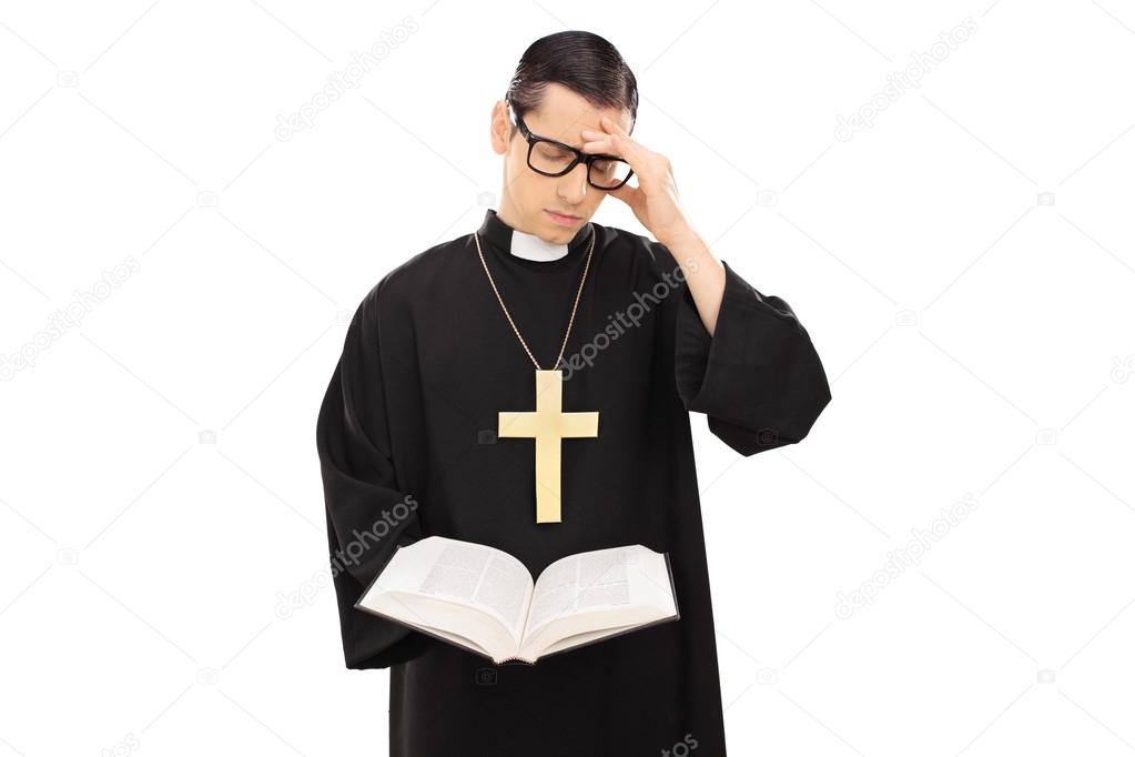 Sad young priest reading the bible